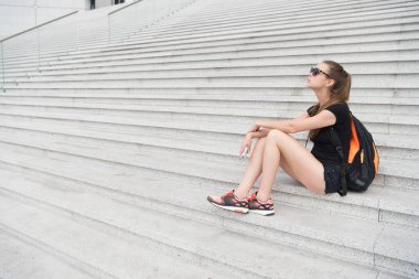 Şehri keşfet. Tatil ve seyahat konsepti. Bekliyorum. Kentsel alan. Turist rehberi gezisi. Tatil fikirleri. Büyük şehirde bir tatil. Kadın dinleniyor. Müze üniversite binası. Kız öğrenci merdivenlerde oturuyor.