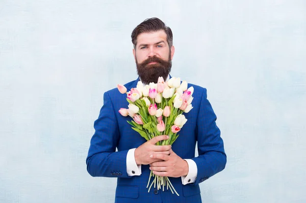 Grüße. Bärtiger Mann mit Tulpenstrauß. Liebesdatum. Frauentag. 8. März. Frühlingsgeschenk. Bärtiger Hipster mit Blumen. Feiern Sie den Frühling. Überraschend. Gentleman mit Tulpen. Der Frühling kommt — Stockfoto