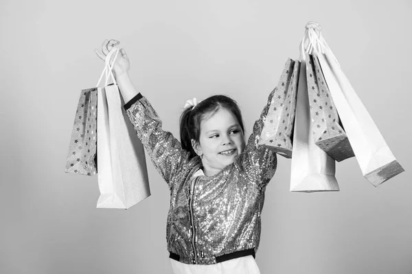 Dívka s nákupní tašky béžové pozadí. Nakupování a nákup. Černý pátek. Sleva na prodej. Nákupní den. Dítě drží balíky. Dětská móda. Překvapivý dárek. Inspirující obchod koupit více — Stock fotografie