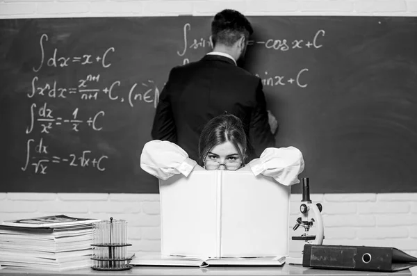 A estudar na aula, como sempre. Bela aula de condução mestre na escola. Professor inteligente com registro de classe sentar-se à mesa enquanto estudante escrever fórmula no quadro. Classe laboratorial — Fotografia de Stock