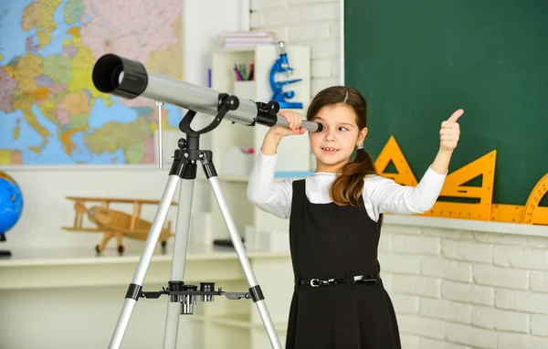 Lerarendag. Een klein meisje met een telescoop. Telescoop op statief. Schoolvakken ingesteld. Astronomieles op school. De ruimte en planeten van nieuwe sterrenstelsels verkennen. School meisje op zoek door telescoop — Stockfoto