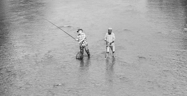 Uma equipa. pesca de pai e filho. Aventuras. recreação e lazer ao ar livre. hobby e atividade esportiva. Isca de truta. dois pescadores felizes com vara de pesca e rede. Grande jogo de pesca. amizade masculina — Fotografia de Stock