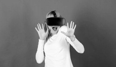 Sanal gerçeklik vizyonu izleyen bir kadın. Şaşırmış genç bir kadın VR deneyimi sırasında havaya dokunuyor. Kırmızı arka planda izole edilmiş sanal gerçeklik kulaklığı kullanan hayrete düşmüş bir kızın portresi..