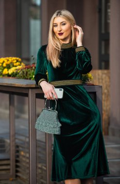 Genç ve özgür. Yeşil kadife elbiseli zarif bir kadın. Cazip kadife tekstil. Seksi iş kadını dışarıda buluşmayı bekliyor. Modern hayat. Kızlar için değerli taş çanta ya da çanta. glam debriyaj aksesuarı