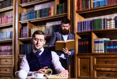 Kütüphanede çay ya da kahve içen, kitap okuyan ciddi adamlar.