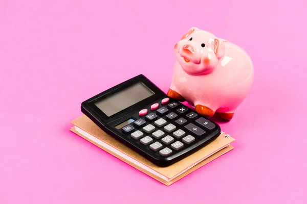 Calcula los beneficios. Hucha de cerdo rosa y calculadora. Puesto de gerente financiero. Economía y finanzas. Intercambio. Mercado de comercio. Control financiero. Administración de empresas. Concepto de crédito —  Fotos de Stock