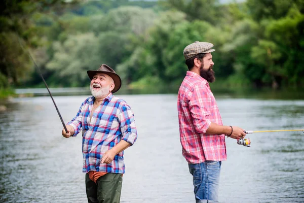 Buenos días. dos pescador feliz con caña de pescar y red. padre e hijo pescando. pasatiempo y actividad deportiva. Cebo para truchas. amistad masculina. vinculación familiar. fin de semana de verano. hombres maduros pescador —  Fotos de Stock