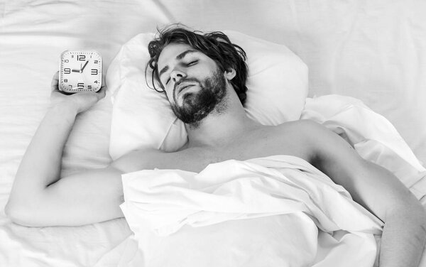 Picture showing young man stretching in bed. Bare feet of a man peeking out from under the cove. Smiling relax sunlight.