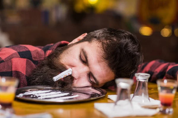 Hipster valt in slaap na het ruiken van cocaïne, drugs. — Stockfoto