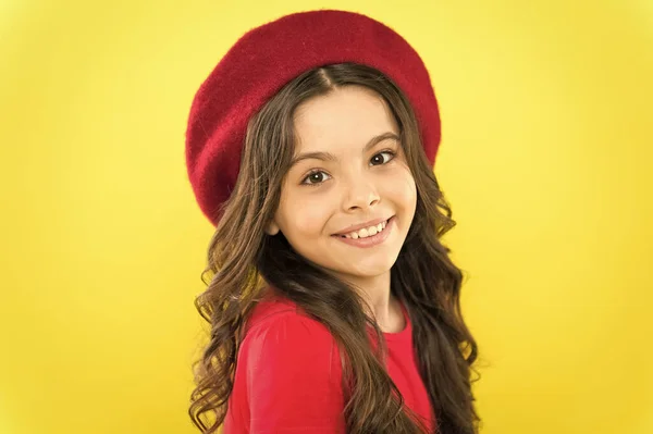 Dziewczyna długo zdrowe lśniące włosy noszą czerwony kapelusz. Mała dziewczynka z długimi włosami. Kid szczęśliwy ładny twarz uroczy kręcone włosy żółte tło. Szczęśliwy i piękny. Porady piękności dla czystych włosów. Uśmiechnięte dziecko — Zdjęcie stockowe