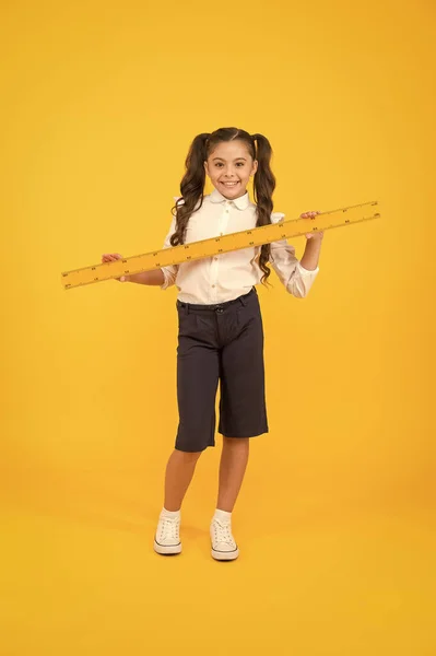 School student study geometry. Tell me about distance. Kid school uniform hold ruler. Pupil cute girl with big ruler. Geometry school subject. Education and school concept. Sizing and measuring