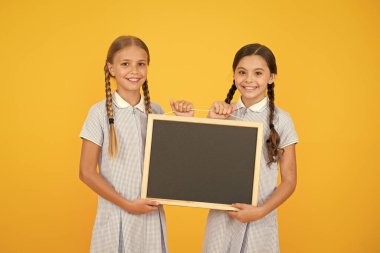 retro üniformalı neşeli arkadaşlar. vintage çocuk moda. Okula geri dön. küçük kızlar tahta tutun. çocuk eğitimi. bilgi sunan kızlar. eski okul. gemide kopya alanı. Reklam