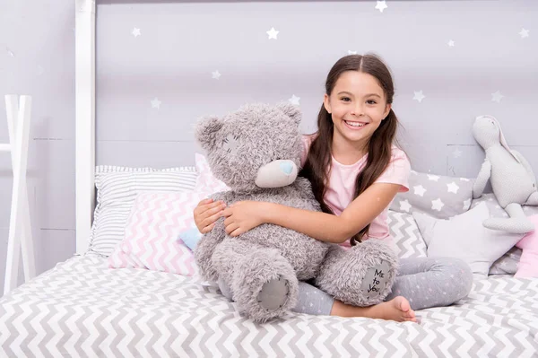 Happiness lives here. Happy child smile on bed. Small girl cuddle teddy bear. Happiness with friend. Playing games. Childhood happiness. Enjoying happiness. Emotional health. Happy childhood — Stock Photo, Image