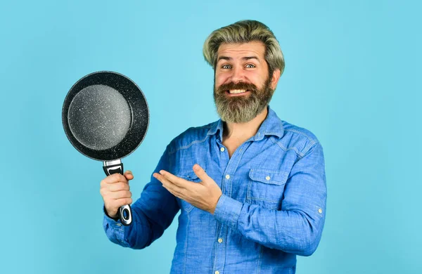 Posant dans la cuisine. homme barbu présentant poêle. cuisiner préparer la cuisine. mari en cuisine. Cuisine concept de nourriture. Tenez la poêle. meilleure qualité. portrait de cuisinier barbu avec outils de cuisine — Photo