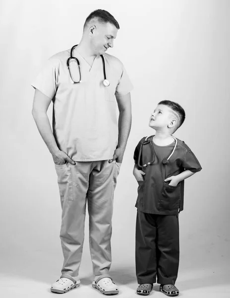 Quiero ser médico como papá. Lindo niño jugar juego médico. Doctor de familia. Concepto de pediatra. Medicina y salud. Padre doctor con estetoscopio e hijo pequeño médico uniforme. Profesión futura — Foto de Stock