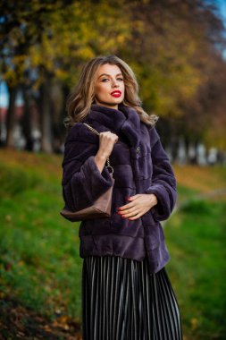 Güzellik standartları. Şık bir bayan sahte kürk giyer. Çok yönlü dokular. moda ve güzellik. Açık havada başarılı bir iş kadını. Sonbahar kadın kıyafeti. Avrupa kışı için giysi. Zarif kadın kürk giyiyor.