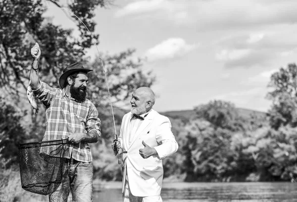 Camping on the shore. fly fish hobby of businessman. retirement fishery. retired dad and mature bearded son. happy fishermen friendship. Catching and fishing concept. Two friends fishing together — 图库照片
