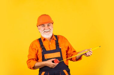Kıdemli müteahhit ölçü olarak bant hattı kullanır. Ölçüm. Mühendis boyutu. İnşaatçı mezura tutuyor. Mühendislik ve onarım Mutlu marangoz. Duvarı boylayan tamirci.