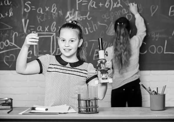 Educatief experiment. Scheikundelessen. Meisjes studeren scheikunde. Microscoop reageerbuizen chemische reacties. Leerlingen bij scheikundeles op schoolbord. Laboratoriumpraktijk. Fascinerende wetenschap — Stockfoto