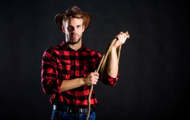 Batı hayatı. Erkek traşsız kovboy siyah arka planı. Şapka tutan adam. Amerikan kovboyunun kementi. Lasso, rodeo yarışmaları kullanırdı. Kementle bağlanabilir ya da paketlenebilir. Acımasız ve kendinden emin.