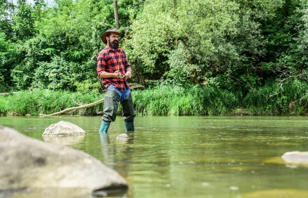 Hobby sport activity. Fish farming pisciculture raising fish commercially. River lake lagoon pond. Trout farm. Fisherman alone stand in river water. Man bearded fisherman. Fisherman fishing equipment — Stock Photo, Image