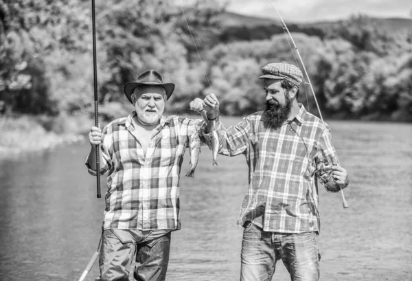 Homem maduro com amigo pesca. Férias. Pescador com cana de pesca. Atividade e hobby. Pesca lago de água doce lagoa rio. Não é desporto, é obsessão. Homens barbudos capturando peixes — Fotografia de Stock