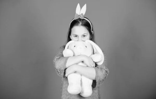 Adéntrate en el espíritu de Pascua. Feliz infancia. Accesorio de orejas de conejo. Precioso conejito juguetón niño abraza juguete suave. Han bendecido Pascua. Conejita con lindo juguete sobre fondo azul. Niño sonriente juego conejito juguete — Foto de Stock