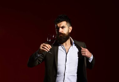 Takım elbiseli adam köpüklü kırmızı şarapla kadeh kaldırıyor.