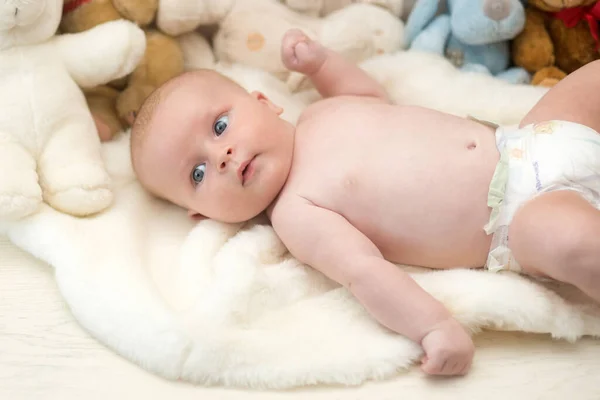 Bambino con occhi azzurri e viso curioso su coperta leggera — Foto Stock