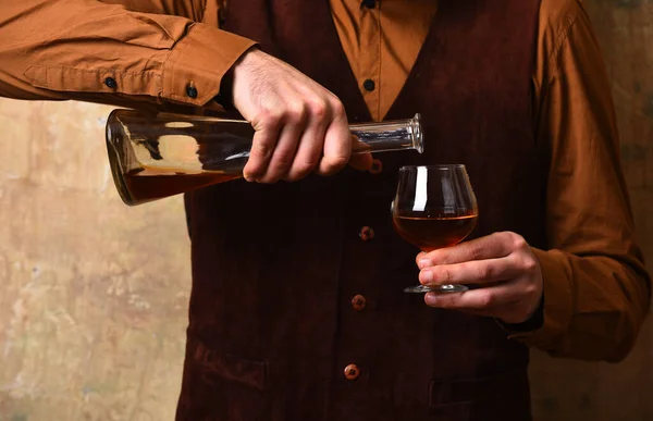 Facet ze szklanką koniaku i butelką. mężczyzna ręce wlać brandy — Zdjęcie stockowe