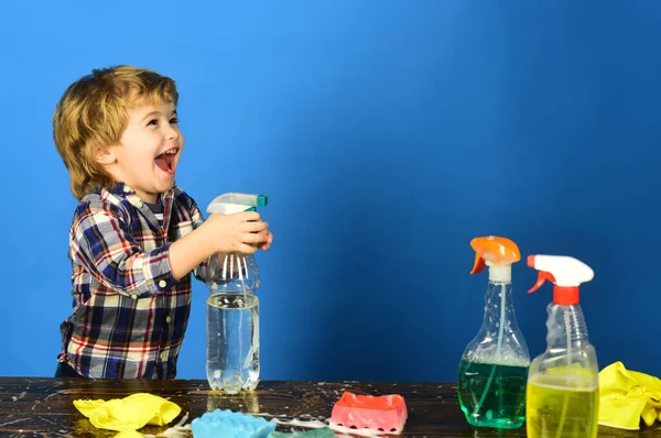 Kid with laughing face holds spray on table. — Stock Photo, Image