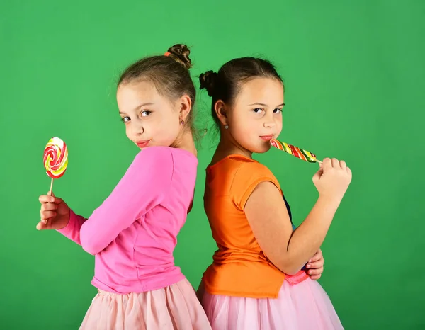 Hermanas con piruletas redondas, de forma larga. Chicas con caras coquetas — Foto de Stock