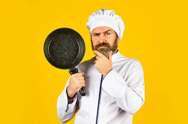 Commerciële keuken. smakelijk gerecht koken. Een man met een baard houdt een koekenpan vast. Koken in de pot. voor het bereiden van voedsel. Een man met baard kookt in de keuken. culinair en keuken. Keukengerei. - Ja. Gezond koken — Stockfoto