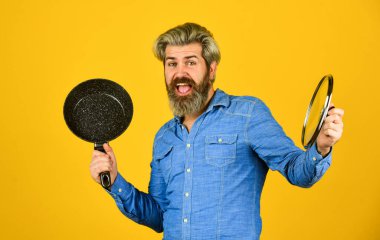 Mutfak gereçleri. Mutfak aletleri. İsimsiz dökme demir pişirme kabı. Tencerenin cam kapağı. Yapışkan olmayan kaplamalı politetrafluoretilen teflon. Adam yeni marka tavayı tutuyor. Sağlıklı yemek pişirmek.