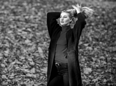 Saçları ne kadar hızlı ve güvenli bir şekilde beyazlatılmış. Kıvırcık saçlardan korunmak için sonbahar saç bakımı önemlidir. Sonbahar parkında şık sarışın kız yürüyüşü. Uzun saç bakım konsepti. Soğuk sarı renk konsepti