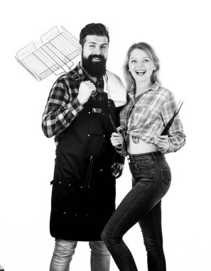 Sakallı adam ve kız barbekü partisine hazırlar. Mutfak konsepti. Aile hafta sonu. Birbirine aşık çiftler barbekü için mutfak aletlerini tutarlar. Açık havada et kızartmak için aletler. Piknik ve barbekü