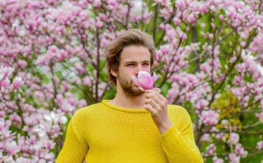 Bahar ilham. Baharın neşesi. Bahar güzeli. Modern hipster çiçekleri sever. İlkbahar konsepti. Adam çiçek parkında rahatlıyor. Botanik bahçesi. Erkek çiçek arka planı. Tazelik ve uyanış