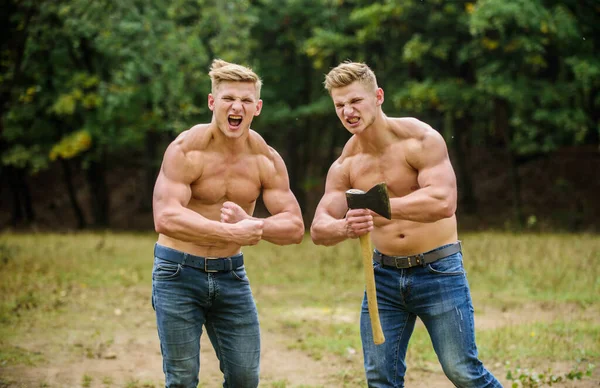 Pohlední bratři. Atletická dvojčata používají sekeru. Muži se svalnatým trupem. Genetický koncept. Přátelství bratrstva. Síla a vytrvalost. Silná mužská přirozenost. Skupinové svalnaté muže se sekerou — Stock fotografie