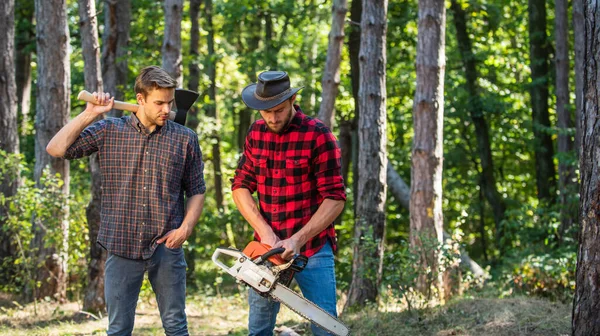 Hommes agriculteurs se détendre dans la forêt. les rangers utilisent du matériel de bûcheron. Bûcheron avec scie et hache. Récoltez du bois de chauffage. randonnées en bois profond. soin de la forêt en vacances. activité estivale ou printanière. C'est la vie — Photo