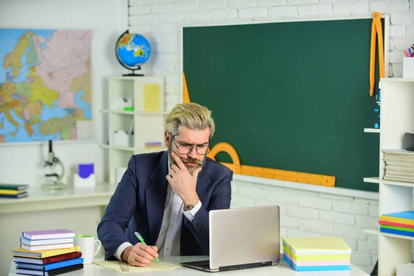 Handsome hipster mature smart educator. Use laptop and internet. Officially submitted application online. School homework. Back to school. Knowledge day. Man work school teacher sit in classroom