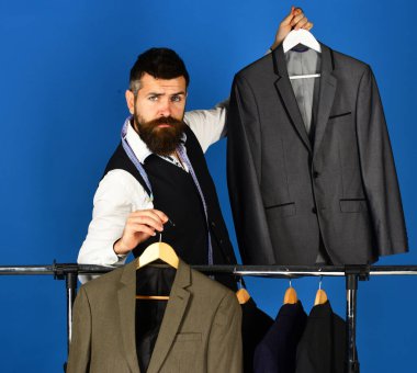 Elbise rafında sakallı bir adam. Tezgahtar veya satıcı