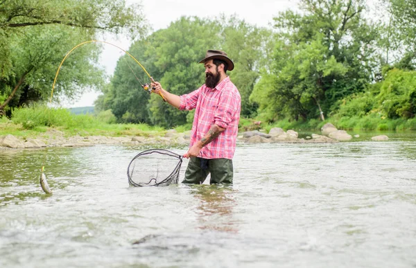 Fishing is astonishing accessible recreational outdoor sport. Fishing hobby. Fishing provides that connection with whole living world. Find peace of mind. Bearded fisher catching trout fish with net