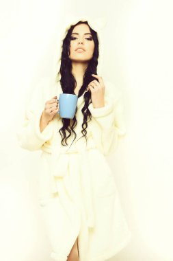 Fincanlı bej kadife bornozla poz veren seksi kız.