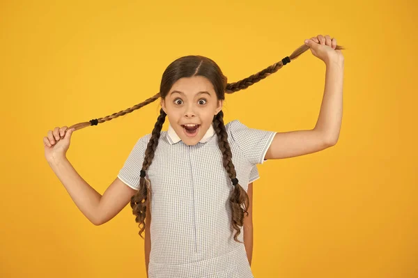 Salone da parrucchiere. Belle scolarette. Ragazze con pettinatura intrecciata. Allegro studentesse sfondo giallo. Bambine che giocano con trecce carine. Belle scolarette. Concetto di ritorno a scuola — Foto Stock