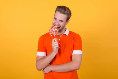 Hiçbir şey tatlıdan daha iyi çalışmaz. Mutlu adam şekerli tatlıyı çubukta ısırıyor. Tatlı tatlı. Sağlıksız atıştırmalıklar. Şekerci ve şekerci. En sevdiği gökkuşağı kıvrımlı tatlı