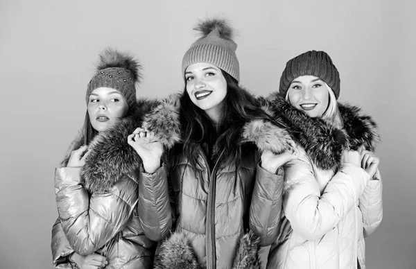 Fashion friends. Winter clothes. Women wear down jacket with furry hood.  Girls smiling makeup faces wear winter jackets blue background. Winter  season. Soft fur. For those wishing stay modern - Stock Image 