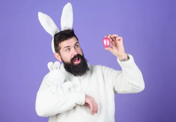 Homem bonito usar orelhas de coelho branco. Coelhinho da Páscoa. Coelho branco símbolo de Páscoa. Um tipo com um brinquedo e um ovo de Páscoa no fundo violeta. Desfrute de ternura. Férias. Páscoa quando você é pai — Fotografia de Stock