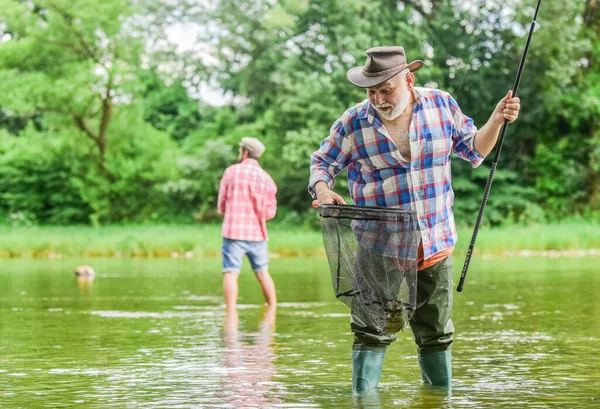 Giornata di pesca. amicizia maschile. legame di famiglia. weekend estivo. due pescatori con canne da pesca, attenzione selettiva. pensionato pescatore uomo maturo. hobby e attività sportive. padre e figlio pesca — Foto Stock