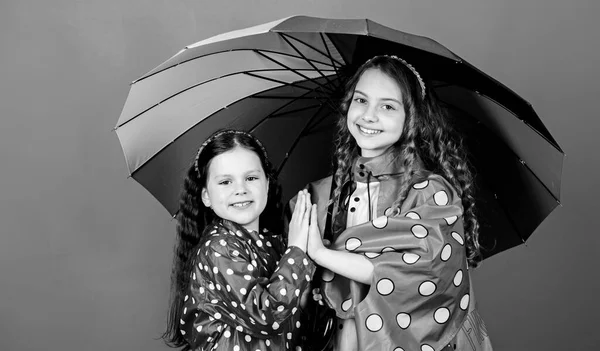Happy childhood. Bright umbrella. It is easier to be happy together. Be rainbow in someones cloud. Walk under umbrella. Kids girls happy friends under umbrella. Rainy weather with proper garments