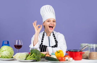 Mükemmel. Mutlu gülümseyen şef çeşitli sebzelerle yemek hazırlıyor. Yeni yemek yapmaya hazırım. Taze vejetaryen salatası. Ticari mutfakta aşçı. Sağlıklı ürünleri olan profesyonel bir şef.